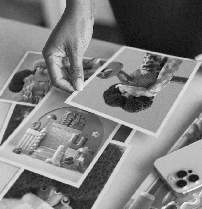 About_Still04 Black-and-white photograph of a hand arranging visual references and printed artwork, illustrating the creative research and art direction process at Morphine.